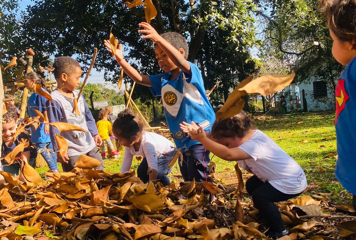 Crianças brincando com folhas secas ao ar livre